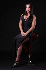 Fototapeta na wymiar young girl in a black dress on a bar stool