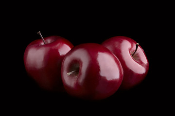 Three ripe dark red apples on a black background