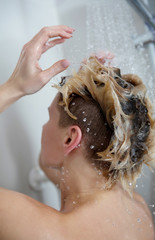 Beautiful naked woman washing her hair while taking shower.