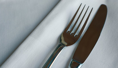 Elegant shiny fork and knife. Luxury restaurant cutlery set on the tablecloth.