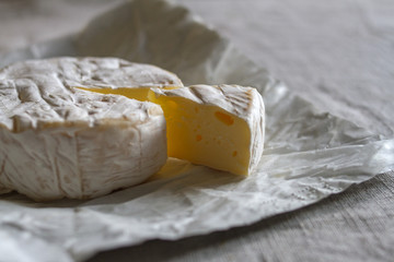 The head of the Swiss Camembert cheese and a triangular piece of cheese on a woven canvas background.
