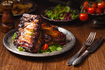 Roasted ribs, served on an old plate. Dark or balck background.