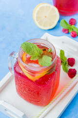 Summer Berry Drink. Lemonade with raspberry lemon, mint in mason jar on blue stone table background. Copy space