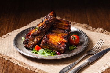 Roasted ribs, served on an old plate. Dark or balck background.