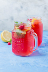 Summer Berry Drink. Lemonade with raspberry lemon, mint in mason jar on blue stone table background. Copy space