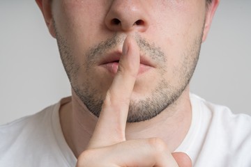 Fototapeta premium Young man has finger on lips and showing be quiet gesture.