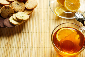 Glass cup of tea with biscuits and lemon on a light wooden background.Cup of tea with lemon and biscuits