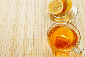 Glass cup of tea with biscuits and lemon on a light wooden background.Cup of tea with lemon and biscuits