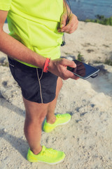 Jogger / runner holding a cellphone with earbuds outdoors.