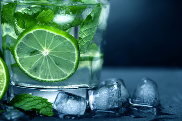Close up the fresh mojito cocktail with fresh lime and mint leaf on black stone background