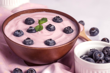 close up the  pink creamy homemade blueberries fruit yogurt with fresh green mint leaf on wooden table background