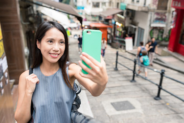 Woman taking selfie with mobile phone in Hong Kong landmark