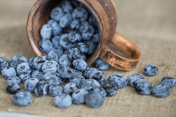Obraz na płótnie Canvas Blueberries sprinkled from rustic cup