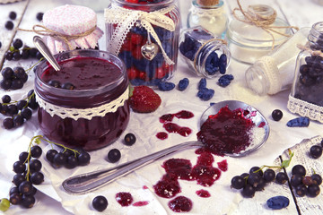 Making jam of black currant berry and honeysuckle berry with vintage jars on the table