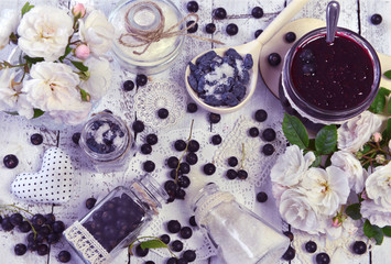Making jam concept with sugar, fresh berry, glass jars, spoon and roses on the table