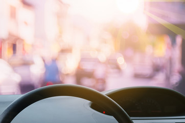 Inside car view ,steering wheel on blur traffic road with colorful bokeh light abstract background.