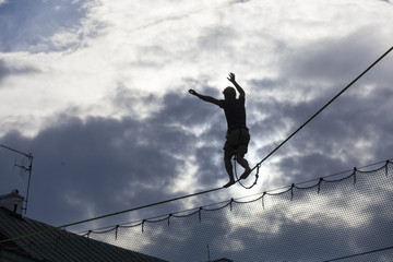 LUBLIN - JULY 28: Man practicing highline in Lublin during Urban High Line festiwal. Highline is a balance sport that consists walking through a rope clamped between two points and great height below.