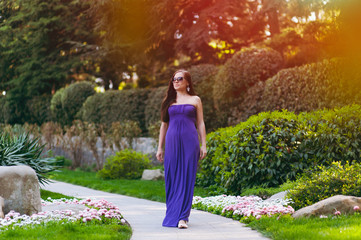 Girl in a long purple dress walking in the park