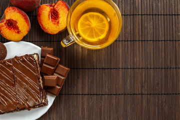 Cake with a cup of tea on a dark wooden background.Dessert of cottage cheese in chocolate glaze