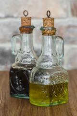 Oil and balsamic vinegar glass bottles with spouts on rustic brick wall background