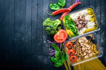 Pasta and buckwheat with meat and fresh vegetables. Healthy Diet Food. Lunch Boxing. On a black wooden background. Top view. Free space for text.