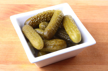 Bowl with pickled gherkins, cucumbers on wooden background close up. Pickles.