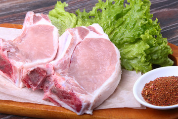 Raw pork steak with spices Leaves lettuce on wooden cutting board. Ready for cooking.