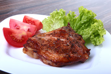 grilled pork chops with tomato, leaves lettuce and ketchup on plate.