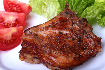 grilled pork chops with tomato, leaves lettuce and ketchup on plate.