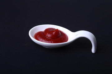 white porcelain bowl of ketchup or tomato sauce isolated on black background.