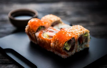 Foto op Plexiglas close up of sushi rolls on black tray and dark wooden table © Ievgen Skrypko