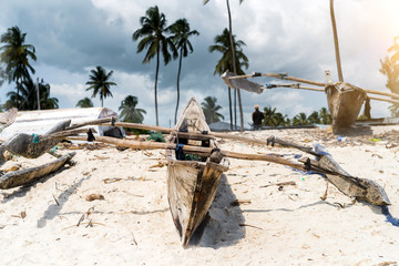 old wooden fishing boat with paddles on a beach of fishing village in Zanzibar