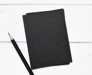 sheets of black paper with pencil on a white table