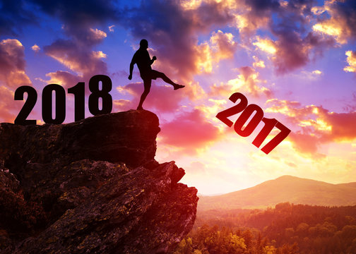 Concept New Year 2018. Silhouette of man kicked to number 2017. 