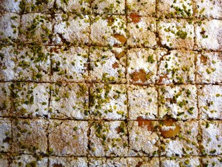 Zitronen-Pistazien Kuchen mit Puderzucker, im Muster geschnitten