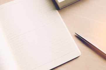 Copy space of notebook pen and book with window light on wood table background.