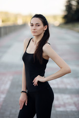 Fototapeta premium Fashion lifestyle portrait young brunette pretty woman posing in the city quay summer sunset evening showing street fashion ideas