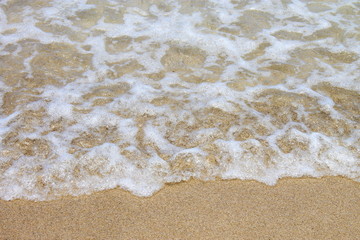 Crystal clear hawaiian water gentle ripples on the shore on a white sand beach.