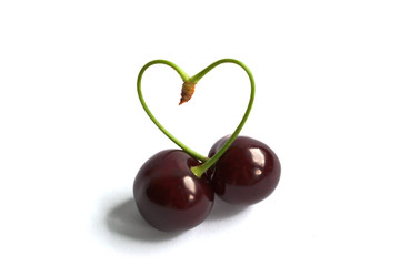 Closeup of cherries with a heart shaped stem on a white background