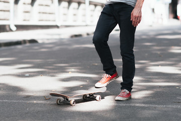 Fototapeta premium Fan active extreme urban sport fo young kid at city street. Unrecognizable skateboarder prepare for practice skateboard trick.