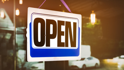 Open sign broad hanging in front of glass door coffee shop.