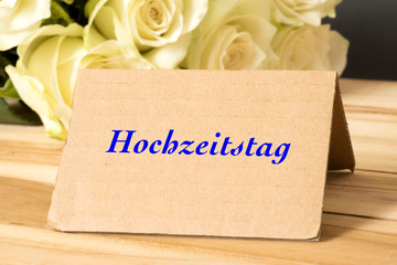 Weisse Rosen und ein Schild mit dem Wort Hochzeitstag