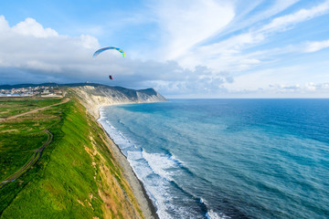 Flying tandem paragliders over the sea and near the mountains, beautiful landscape view
