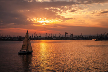 Sailing yacht enters the harbor at the sunset