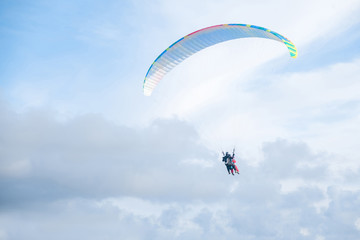Paragliders in bright blue sky, tandem of instructor and beginner