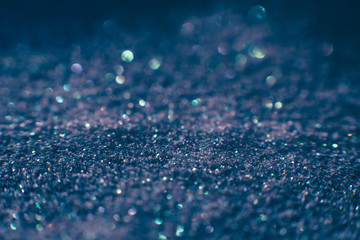 Abstract shining glitters violet holiday bokeh background with copy space. Defocused lights backdrop, selective focus with shallow depth of field. Christmas and New Year wallpaper decorations concept.