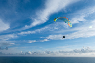 Flying a tandem paraglider over the sea with views of the horizon
