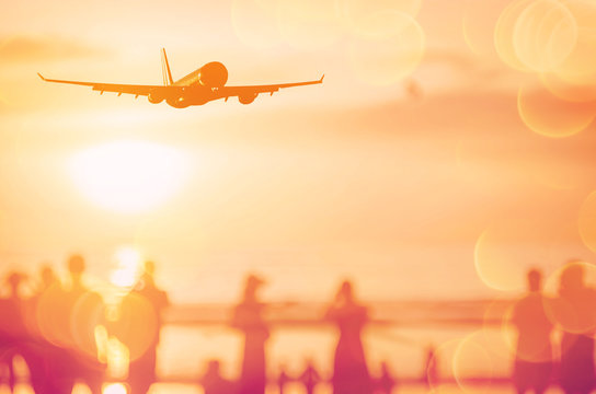 Airplane Flying Over Blur People Relax On Tropical Sunset Beach With Bokeh Sun Light Wave Abstract Background.