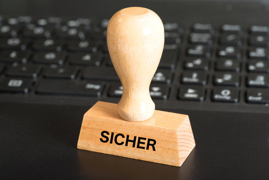 Ein Computer und ein Stempel mit dem Aufdruck Sicher