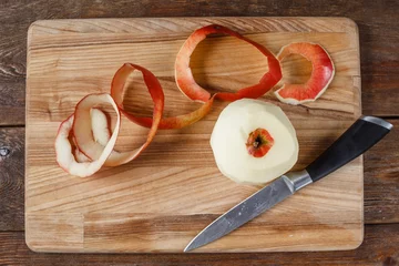 Fotobehang Top view of single red apple paring by knife. Fresh fruit lay on wooden desk. Healthy food, dietary, cooking concept © golubovy